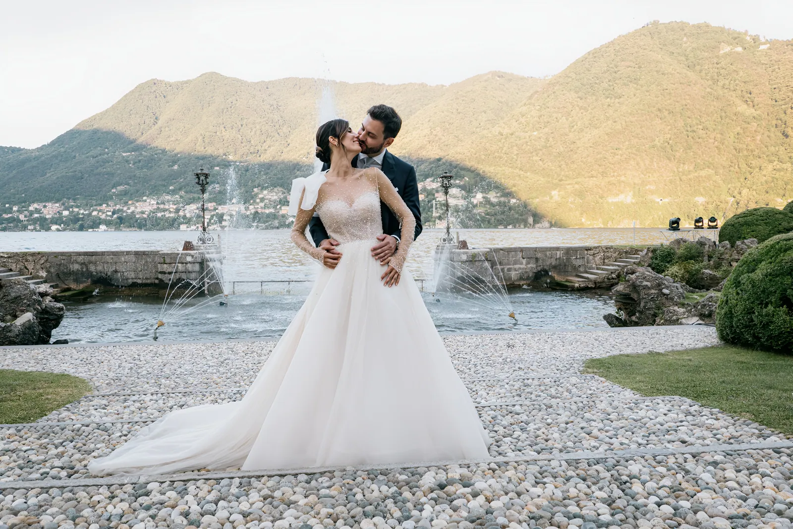 Il bacio degli sposi con il lago e le montagne alle spalle